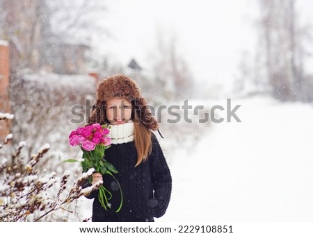 Portrait of a young girl in black clothes .Winter picture white background, live bright roses in hands              