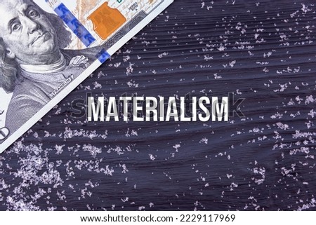 MATERIALISM - word (text) on a dark wooden background, money, dollars and snow. Business concept (copy space).