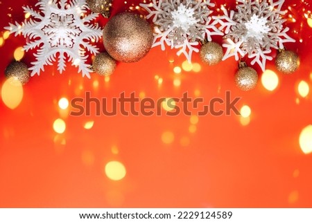 Christmas decorations, white snowflakes and golden balls, on a red background with lights. Flat lay