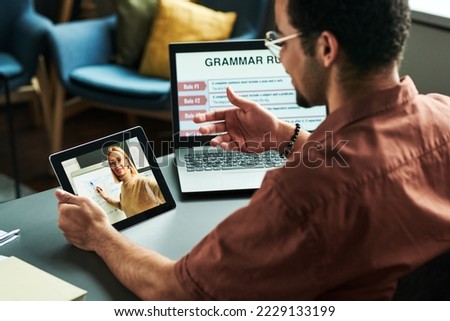 Young student communicating with teacher on tablet screen making presentation of new English grammar subject during online lesson Royalty-Free Stock Photo #2229133199