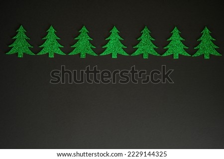 Row of green glitter Christmas trees on a black background
