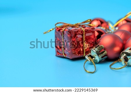 Christmas and New Year background. Golden gift box. Glass balls hang on a ribbon. Bright winter holiday composition. Postcard, banner, poster