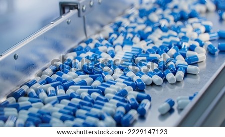 Blue Capsules are Moving on Conveyor at Modern Pharmaceutical Factory. Tablet and Capsule Manufacturing Process. Close-up Shot of Medical Drug Production Line. Royalty-Free Stock Photo #2229147123