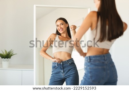 Self confidence concept. Happy caucasian lady pointing finger at her reflection in mirror, having fun while posing after great weight loss, free copy space Royalty-Free Stock Photo #2229152593