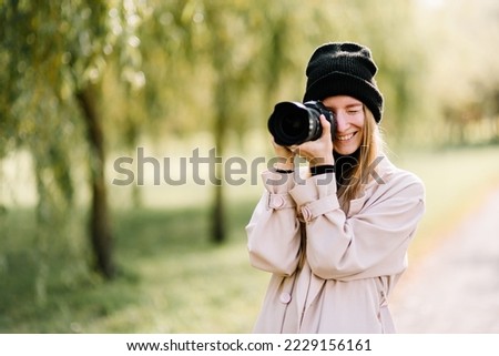 young beautiful girl is resting in nature with camera. woman photographer walking in the park on an autumn day