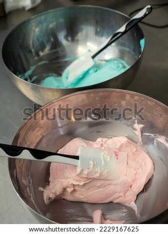chef preparing pink and blue filling for piping bag for frosted icing cake decoration