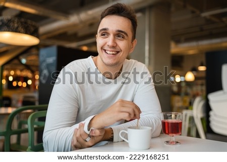 One man young adult Caucasian man sit at cafe or restaurant alone looking to the side having a cup of coffee real people copy space happy smile Royalty-Free Stock Photo #2229168251
