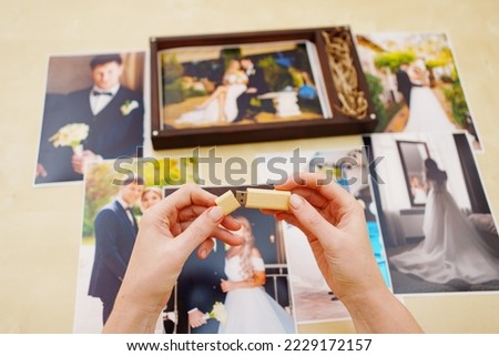 printed wedding photos, a wooden box and hands with a flash drive. the concept of preserving the memory of an important event, the services of a professional photographer for the celebration.
