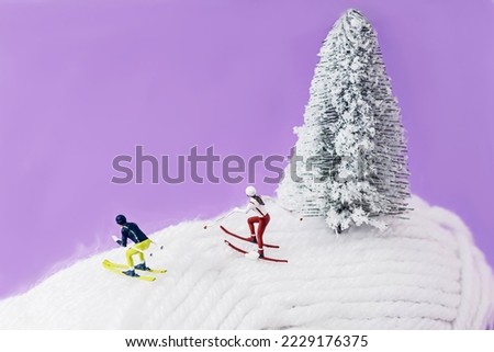 Two mini skiers and a snowy Christmas tree on a ball of white wool. Surreal creative concept for winter holidays resort advertisement. Design for season greetings banner or card. Macro photography