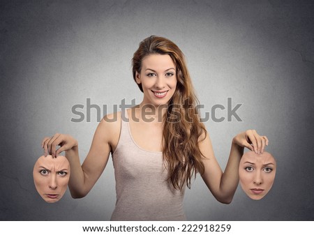 Liar. Portrait beautiful happy girl holds two masks isolated grey wall background. Human face expressions, emotions, feelings, bipolar state of mind concept Royalty-Free Stock Photo #222918259