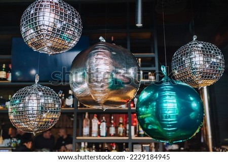 Beautiful round airy silver, multi-colored foil balloons with helium hang indoors at a party, disco. Photography, holiday, decor.