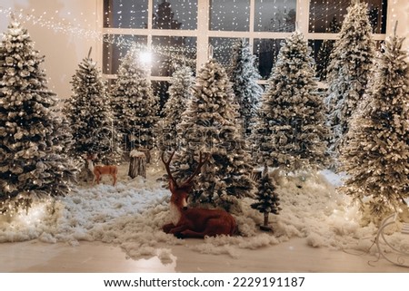 New Year's photo zone with snow near a cafe bakery. Christmas decor: toys, Christmas trees, bench, garland, glowing light bulbs. festive mood. picture for postcard