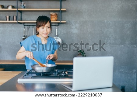 Asian woman taking online cooking class on computer