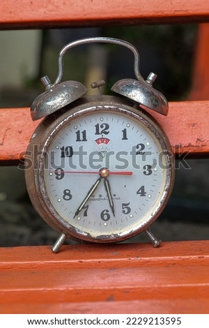 Old alarm clock lying on a garden chair