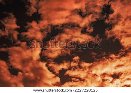 A stunning celestial landscape of the sky at sunset with a silhouette of the face of a fairy-tale character in a mask peeking through. Selective focus.