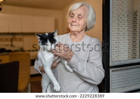one woman senior old female caucasian pensioner standing at home alone waist up portrait look to the camera hold cat pet dementia alzheimer's disease and depression concept emotion copy space