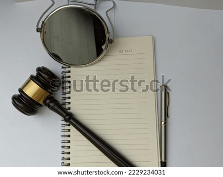 Blank notebook with judge gavel, mirror and pen on isolated white paper background.