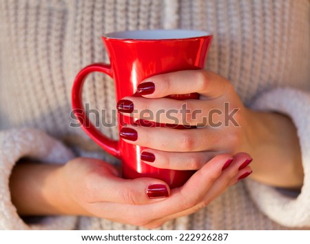 Picture of a woman's hand holding a red coffee mug