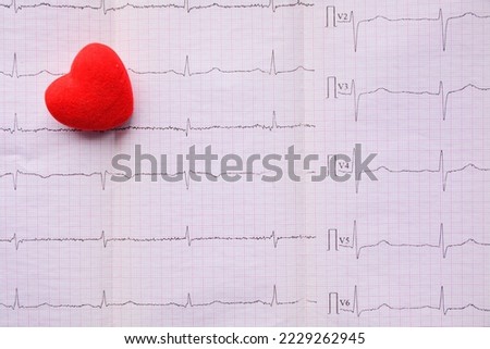 red heart on sheet of pink millimeter paper with diagram of medical examination of the heart on an electrocardiogram with copy space. Medical concept Royalty-Free Stock Photo #2229262945
