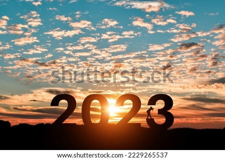 Silhouette of photographer taking photos in 2022 years at sunrise or sunset background. Idea for happy new year 2023.