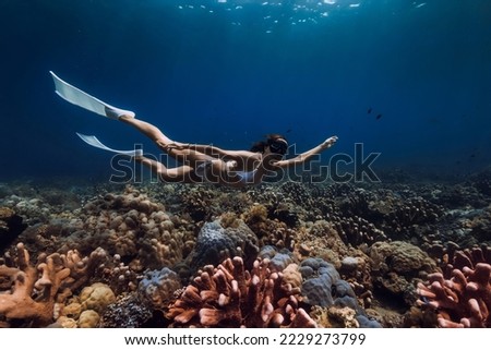 Woman freediver glides with fins over corals. Freediving in deep blue ocean Royalty-Free Stock Photo #2229273799