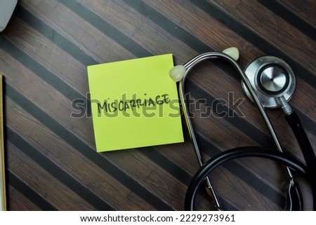 Concept of Miscarriage write on sticky notes with stethoscope isolated on Wooden Table.