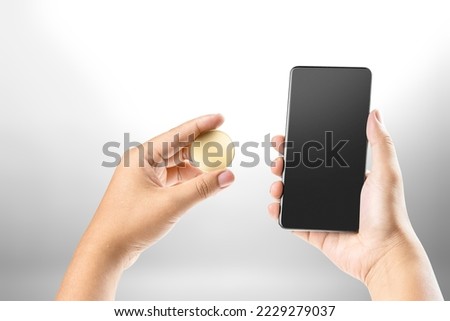 Hand holding mobile phone and coin on white background