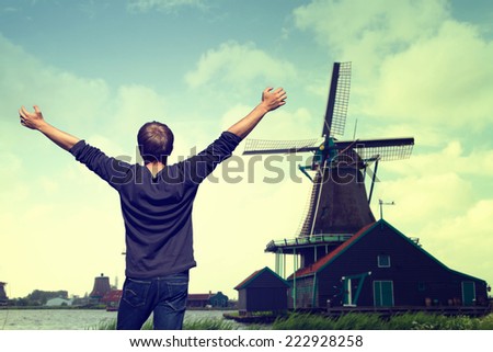 young energetic man traveler enjoys life, liberty and the views of European Wildlife and Dutch windmills. lifestyle. vintage retro photo . Zaanse Schans Fall , Netherlands