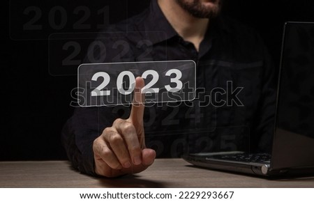 Choosing the new fiscal year 2023. The male hand chooses the new 2023 year. Choosing a new year and new business goals