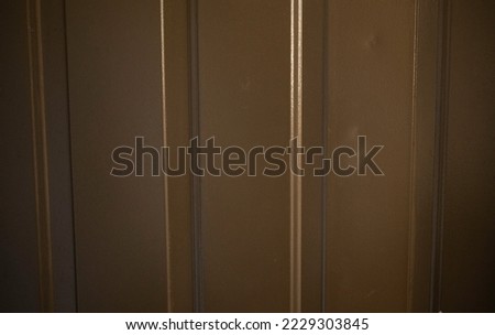 A background texture of a scratched wooden door with cheap brown paint and light shining off of it for product placement or graphic designs.