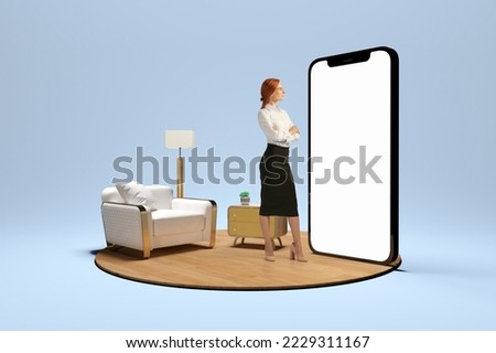 New opportunities, modern lifestyle. Young girl standing in front of huge 3d model of cellphone with blank white screen and thinking isolated on blue background. Online working, payment, new app Royalty-Free Stock Photo #2229311167