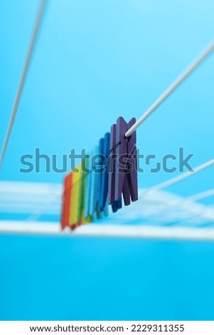 Multicolor clothespins hanging on drying rack on blue background