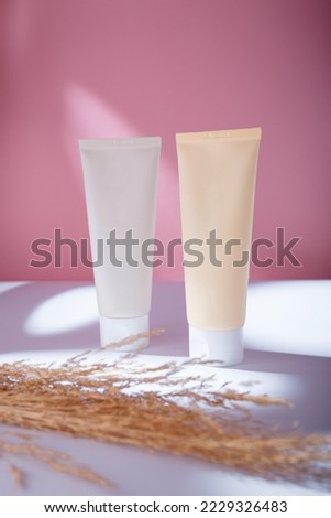 Beige and white two tubes of hair conditioner and shampoo mockup, no label template, pink backdrop in harsh light. Korean cosmetics containers