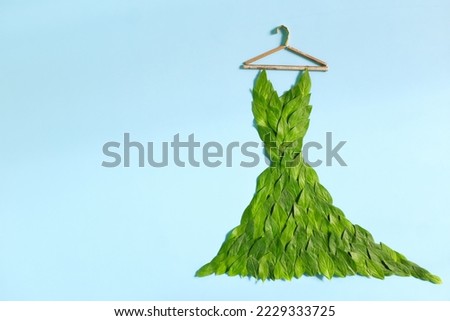 Sustainable and eco friendly fashion concept. Dress made of fresh green leaves in blue background. Royalty-Free Stock Photo #2229333725