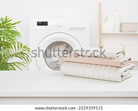 Stack of clean bedding sheets on blurred laundry room background Royalty-Free Stock Photo #2229339131