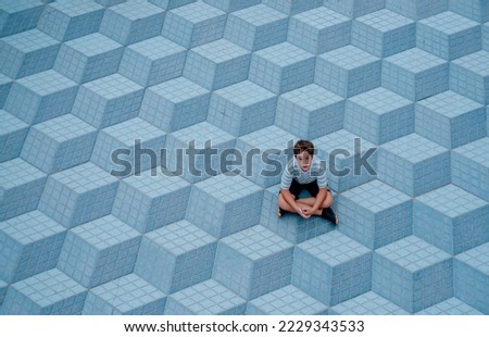 A child seated on a background of blue cubes