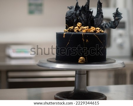 pastry chef finishing horror black muertos birthday cake decorating with golden edible skulls and black rice paper sails