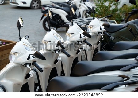 Motorcycles for rent or for sale on the city street. Lots of white scooters to ride. Royalty-Free Stock Photo #2229348859