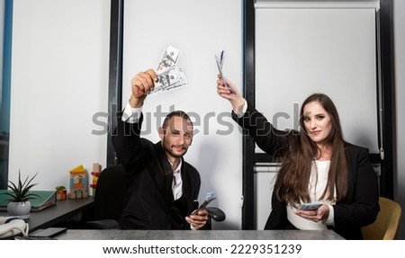 Portrait of business people throwing currency note. Bearded Jewish man in Yarmulke sit at desk holding hundred dollar bills. Israeli woman making money rain in office a stack of dollars in hand