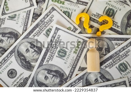 Money banknotes, wooden doll figure and question mark symbols. Where to invest money concept