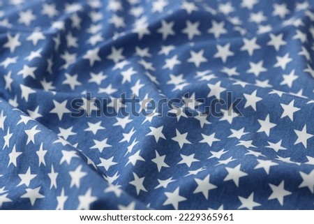 Close-up of blue wavy fabric with white stars texture background. Stars seamless pattern backdrop