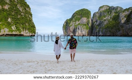 Thai women and caucasian men walk on the beach of Maya Bay beach Koh Phi Phi Thailand with turqouse colored ocean. 