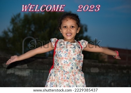 Baby girl or kid open her arms to welcome new year 2023. Greets the new year. Selective focus and background blur.