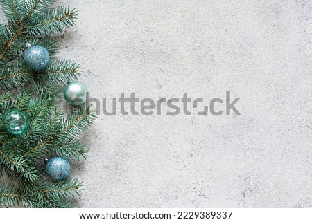 Christmas background with fir branches and decorations (toys) on a gray, festive mood, gift season. Winter holidays concept. Top view and copy space.