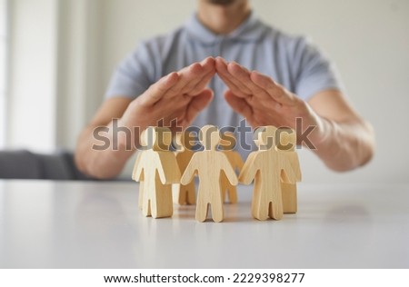 Close up employer holding hands over little pawn people. Responsible corporate business manager protects employees, guards their interests and creates equal and safe environment for developing talents Royalty-Free Stock Photo #2229398277
