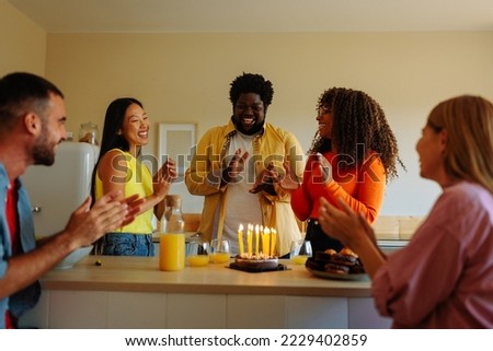 A group of young diverse friends are at home celebrating a birthday party of one of them in a small gathering of close friends.