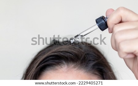 woman applying serum oil on wet hair with pipette or using white comb to disentangle isolated.healthy strong hair,growth stimulation stop fall shiny.top of head forehead lateral view.after pregnancy Royalty-Free Stock Photo #2229405271