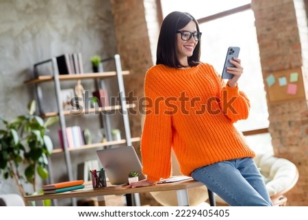 Photo of happy positive lady dressed orange pullover selling goods modern gadget indoors workshop workplace workstation