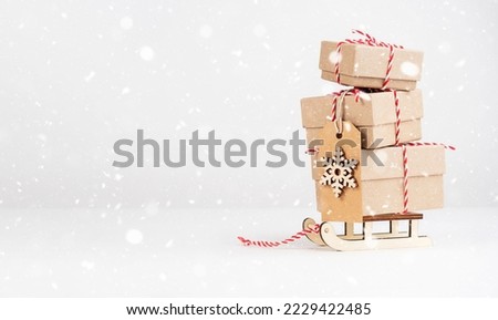 Boxes with gifts on a sled on a light background with space for text. Snow. Gifts for New Year and Christmas.
