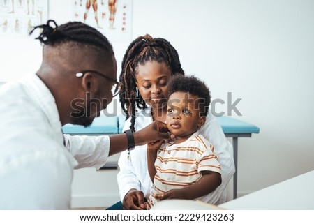 African male pediatrician hold stethoscope exam child boy patient visit doctor with mother, black paediatrician check heart lungs of kid do pediatric checkup in hospital children medical care concept Royalty-Free Stock Photo #2229423263